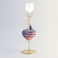 Patriotic heart rhinestone keychain with American flag detail and blue tassel displayed on gold retail stand with hang tag