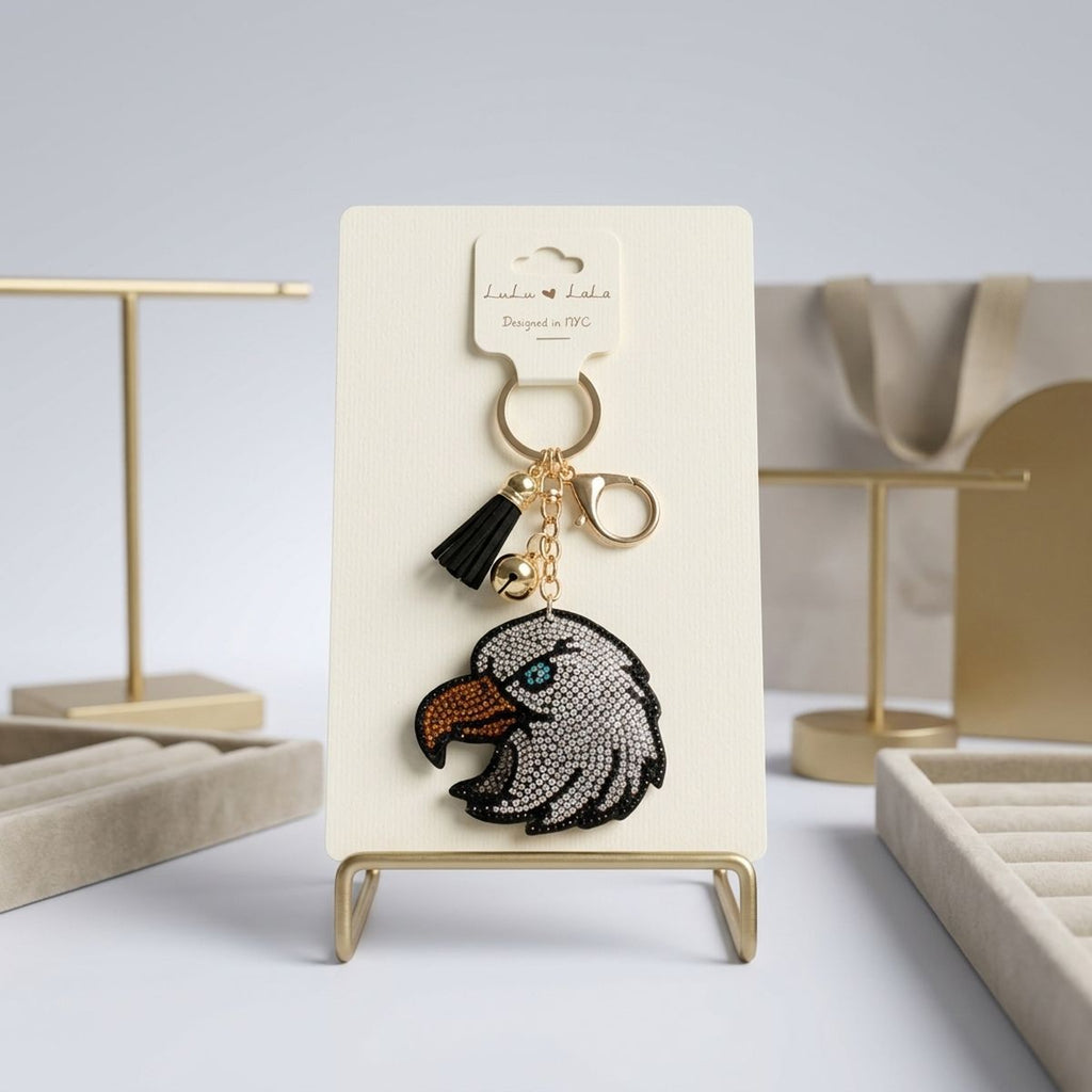 Patriotic bald eagle rhinestone bag charm keychain with black tassel and gold hardware on display stand
