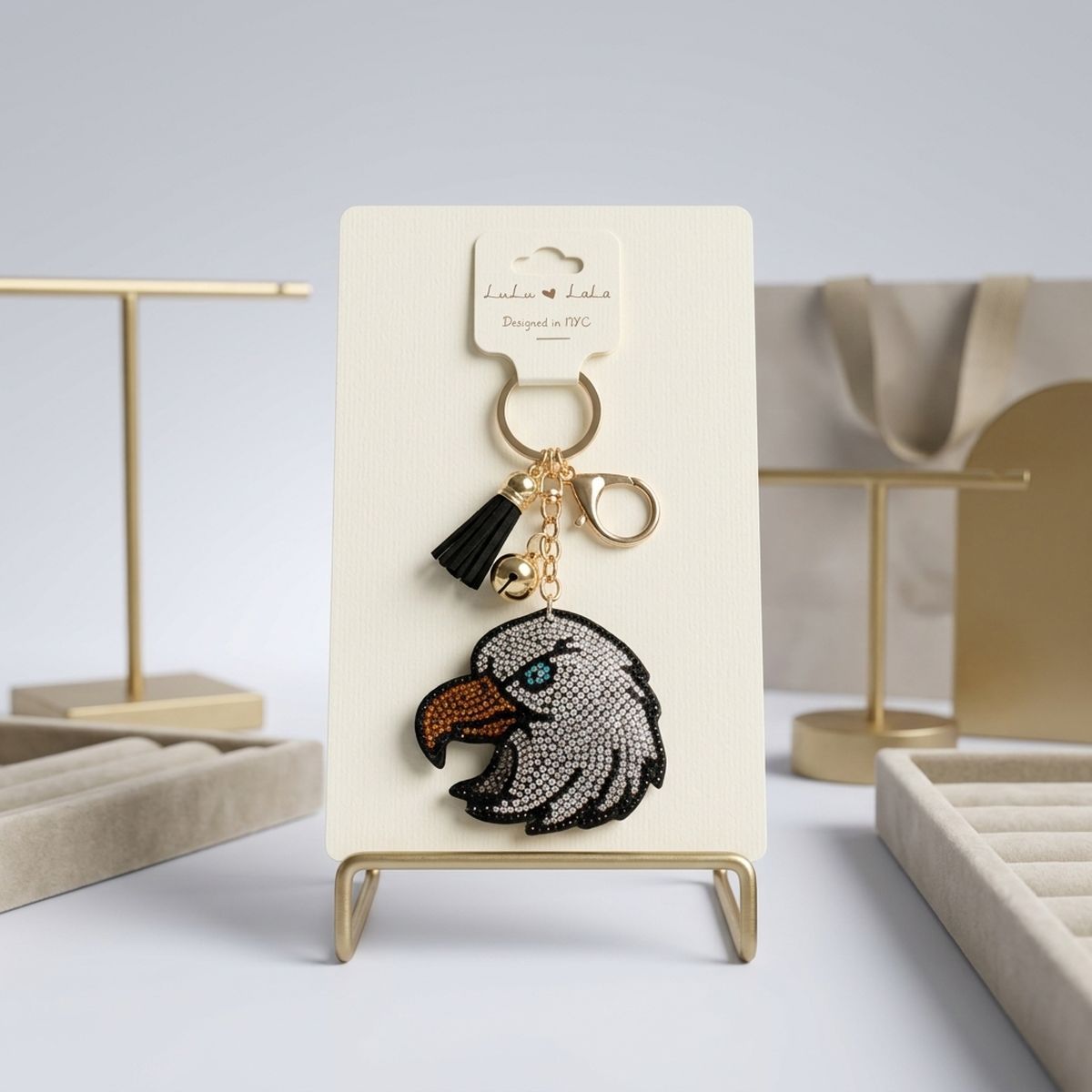 Patriotic bald eagle rhinestone bag charm keychain with black tassel and gold hardware on display stand