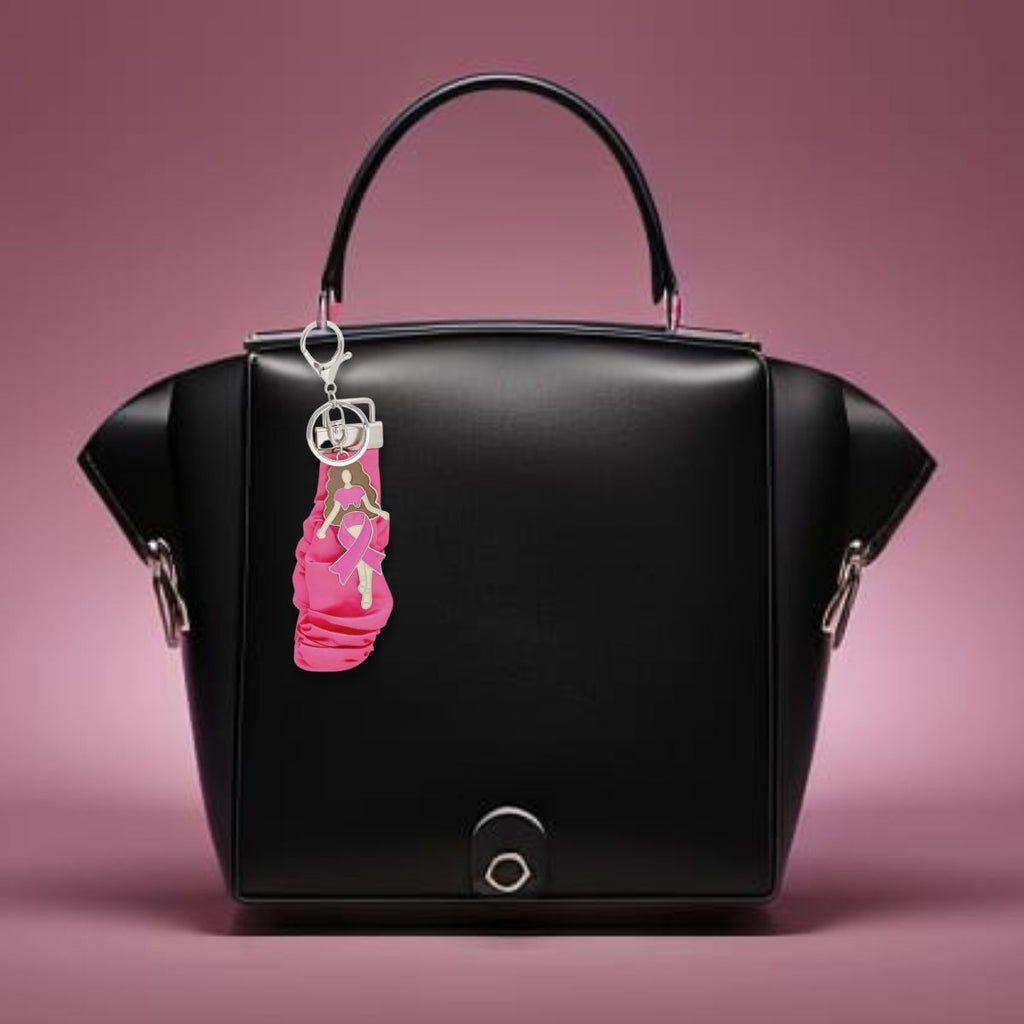 Pink ribbon scrunchie wristlet keychain clipped to a black leather handbag as a purse charm