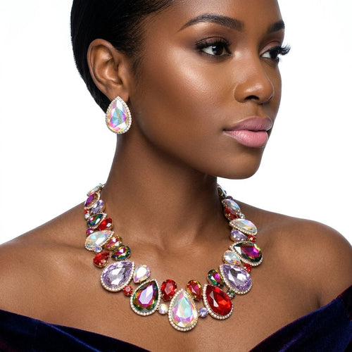 Close-up of women's multicolor rhinestone halo collar necklace with red, lavender, and iridescent glass teardrop gems in gold tone, worn with matching stud earrings on off-shoulder neckline
