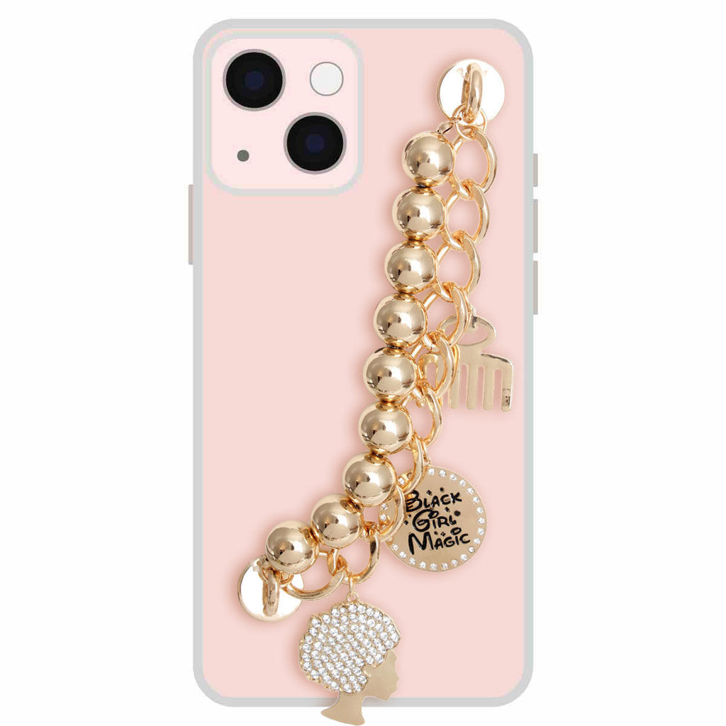 Gold Black Girl Magic phone wrist strap attached to pink iPhone case, featuring gold metal ball beads on gold curb chain, rhinestone afro silhouette charm, round Black Girl Magic engraved disc charm, and gold afro pick comb charm