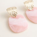 Close-up of light pink and white marbled resin earrings with hammered gold-tone geometric tops