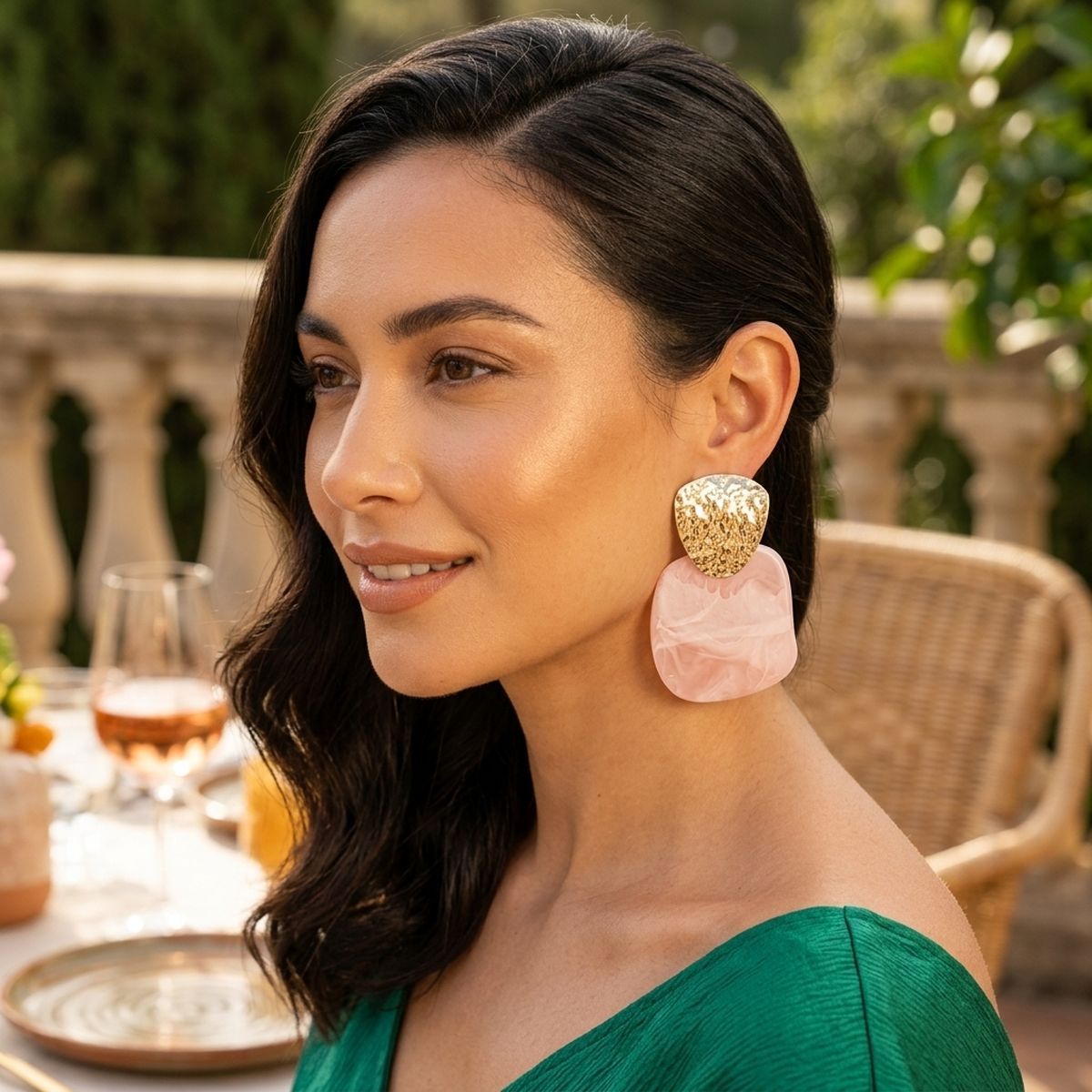 Model wearing light pink marbled resin and hammered gold-tone drop earrings outdoors