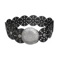 Black vegan faux leather wide western concho belt coiled on white background, overlapping circular disc panels with silver grommet and rivet punch-out details, large engraved distressed silver round concho buckle with floral and paisley etching at center
