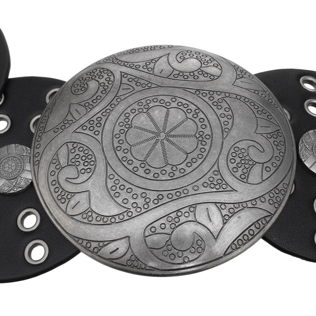 Closeup of large engraved distressed silver round concho buckle with intricate floral and paisley etched pattern, antique silver finish, black vegan faux leather disc panel with silver grommet punch-out details visible at sides, white background
