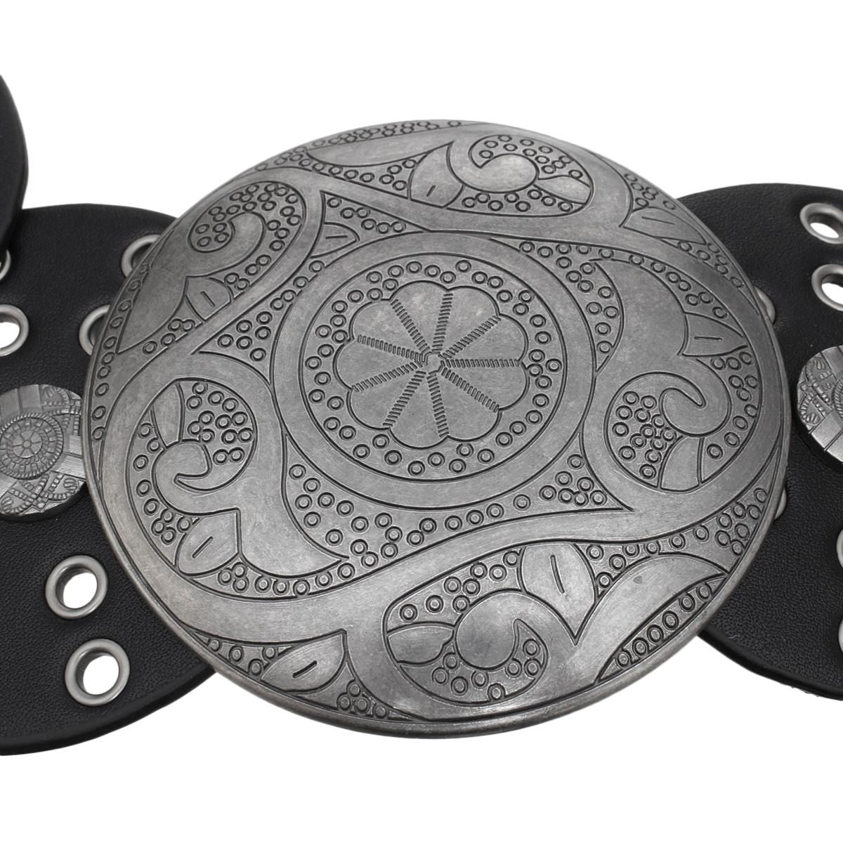 Closeup of large engraved distressed silver round concho buckle with intricate floral and paisley etched pattern, antique silver finish, black vegan faux leather disc panel with silver grommet punch-out details visible at sides, white background