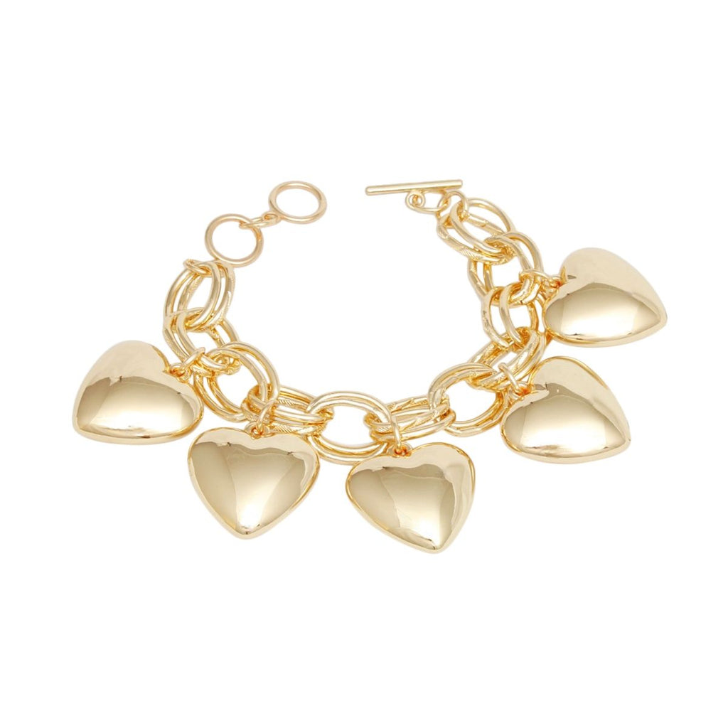 Overhead flat lay of a chunky gold tone double oval link chain charm bracelet on a white background. Five oversized puffy hollow polished gold heart charms dangle from the interlocking double oval links. A round ring and toggle bar closure is visible at the top right of the bracelet.