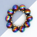 Black rainbow iridescent bubble bead bracelet with gold-tone spacers arranged in a circle on a diagonally divided gray and white background