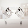 Pair of oversized hammered silver-tone diamond-shaped stud earrings with round center cutouts and dangling cross charms on a clear display stand