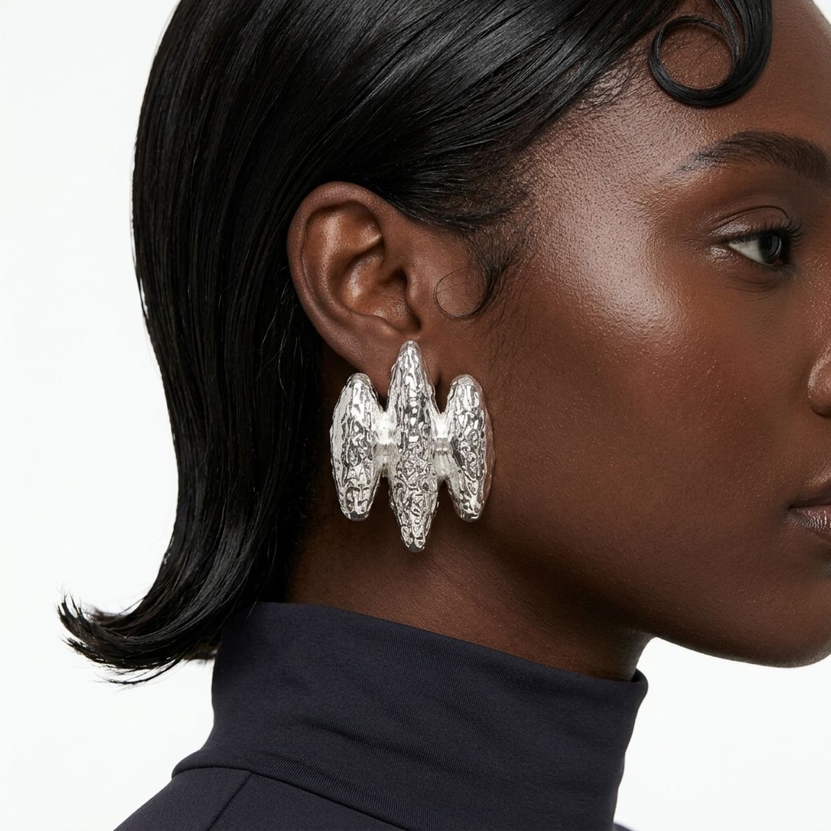 Close-up of a model wearing silver textured triple-rib clip-on earrings with a sculptural triple-rib design.