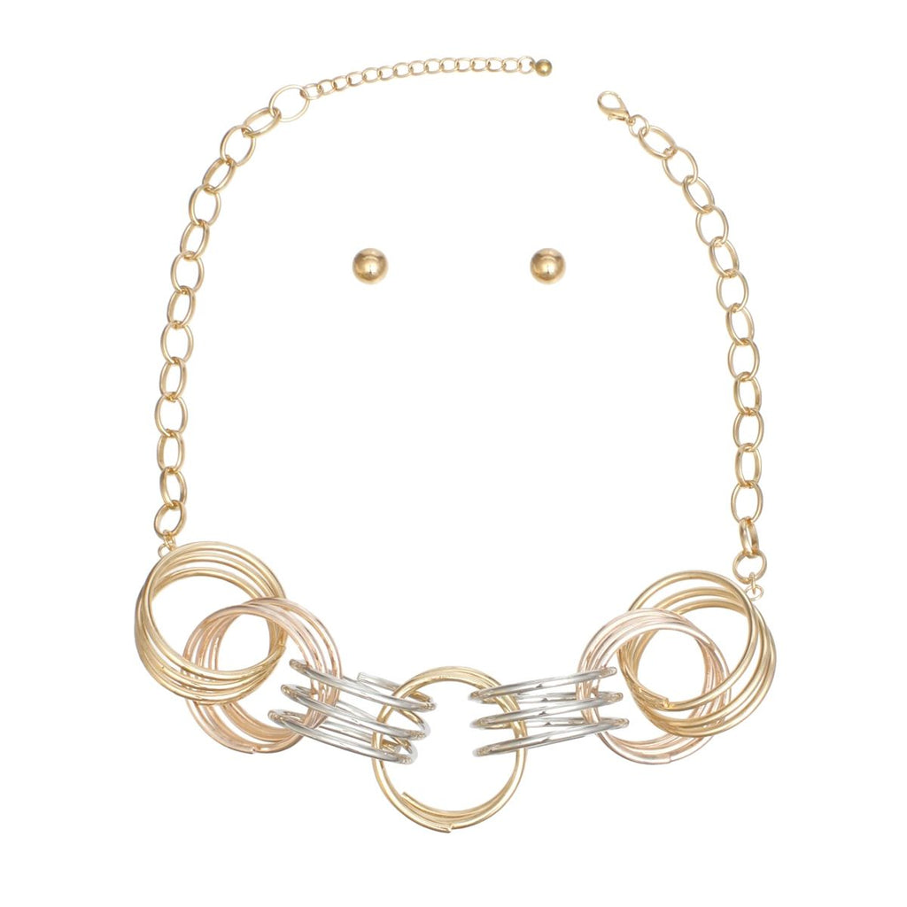 Overhead flat lay of a mixed metal multi-wire open ring collar necklace on a white background. The collar section features five linked oversized multi-wire open rings in gold, rose gold, and silver tone. A gold tone oval link chain with lobster clasp and 3-inch extender is visible at the top. Two small gold tone ball stud earrings with butterfly post backings are displayed above the necklace.