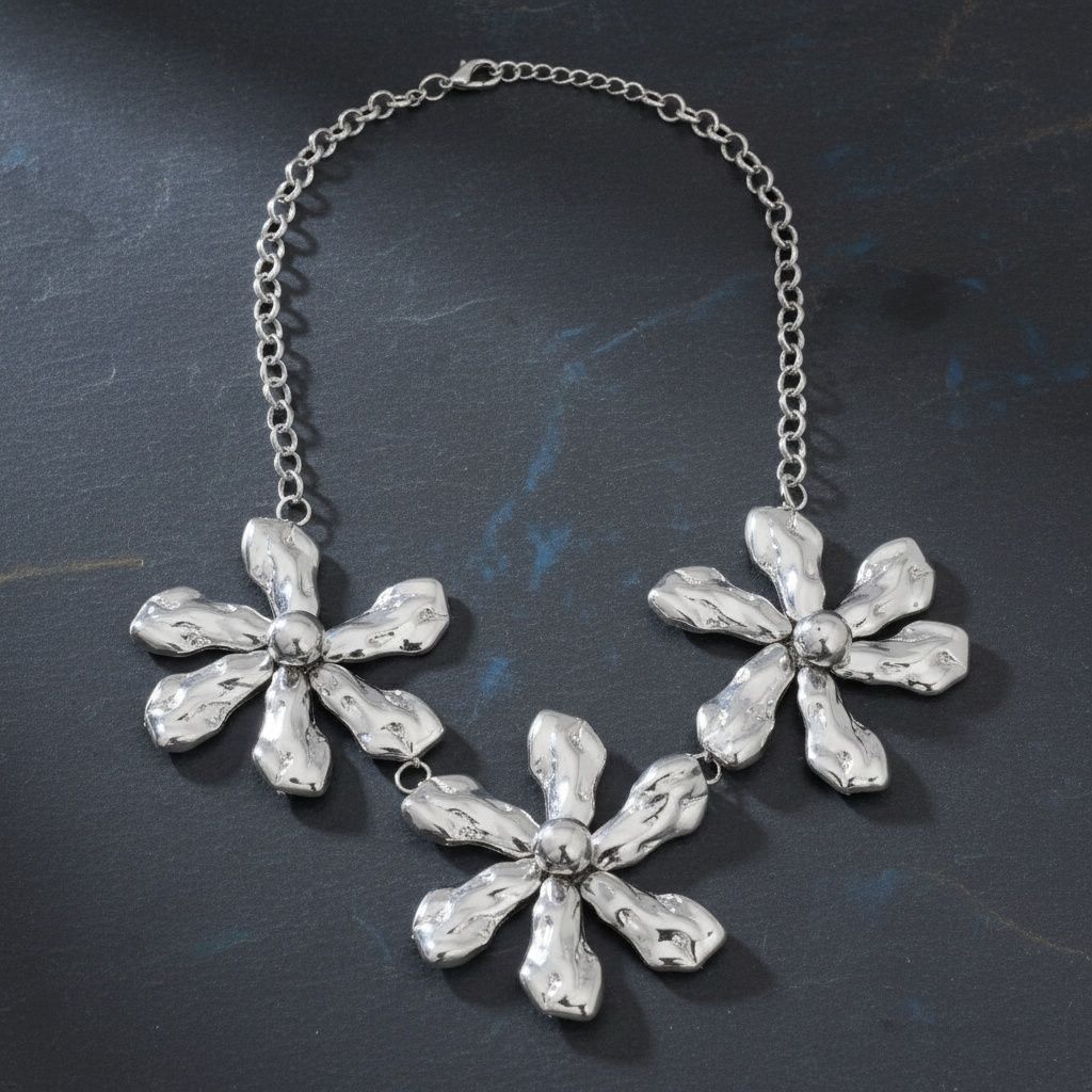 Silver-tone chunky triple floral bib necklace with hammered organic acrylic petals, raised dome centers, and silver round link chain with lobster clasp, displayed on dark blue-grey slate background