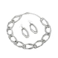 Overhead flat lay of an oversized diamond cut geometric open link chain necklace in rhodium silver tone arranged in a circle on a white background, with a lobster clasp and 2-inch extender chain visible at the top right. Two matching open oval drop earrings with fish hook backs featuring alternating smooth polished and textured diamond cut finishes are displayed in the center of the necklace loop.