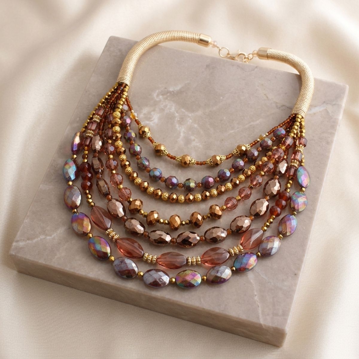 Layered multicolor crystal bead necklace with a gold-tone coil collar displayed on a stone jewelry stand