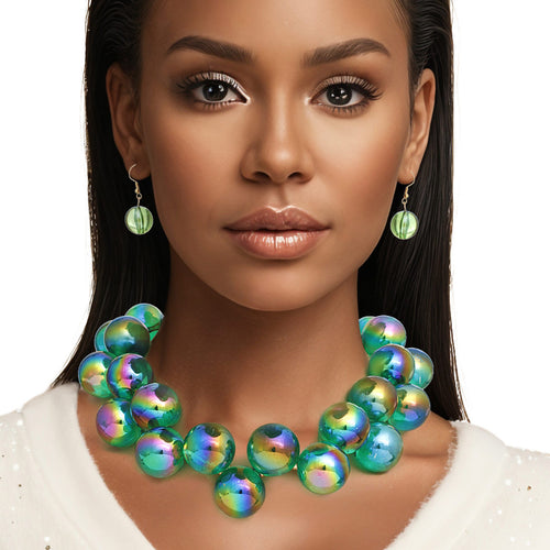 Model wearing a green iridescent bubble bead statement necklace and green bead drop earrings with a white top against a white background