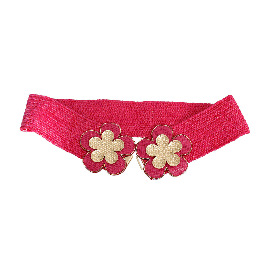 Fuchsia wide woven raffia stretch belt laid flat and open on white background, double gold basket-weave flower hook closure showing two five-petal flowers with gold crosshatch texture centers, fuchsia raffia petal surrounds with gold beaded trim edging and center hook mechanism, full woven raffia body visible