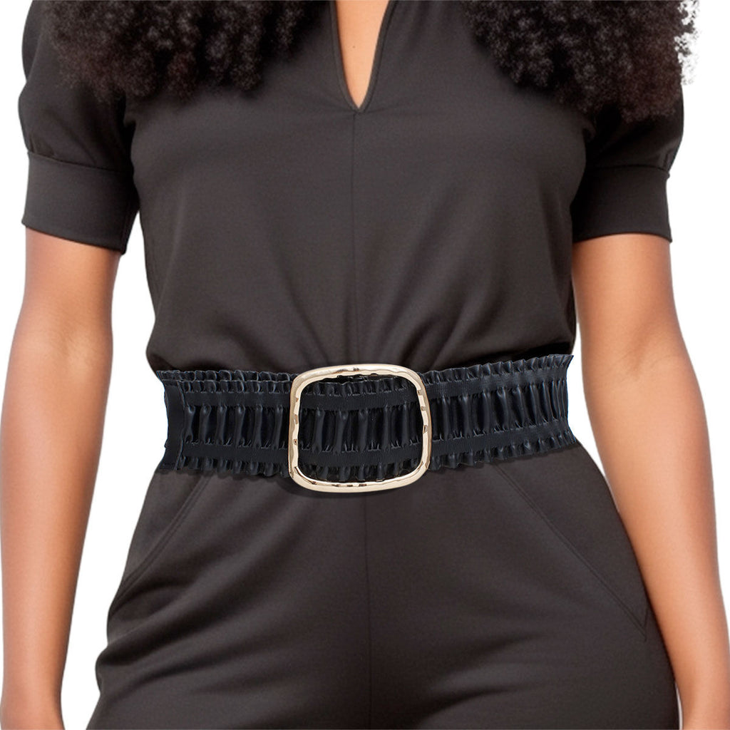 Black wide ruched vegan leather stretch belt worn on woman's waist over dark olive V-neck short sleeve jumpsuit, chunky hammered gold open square buckle at center, ruffled black vegan leather panels with elastic stretch construction, white background