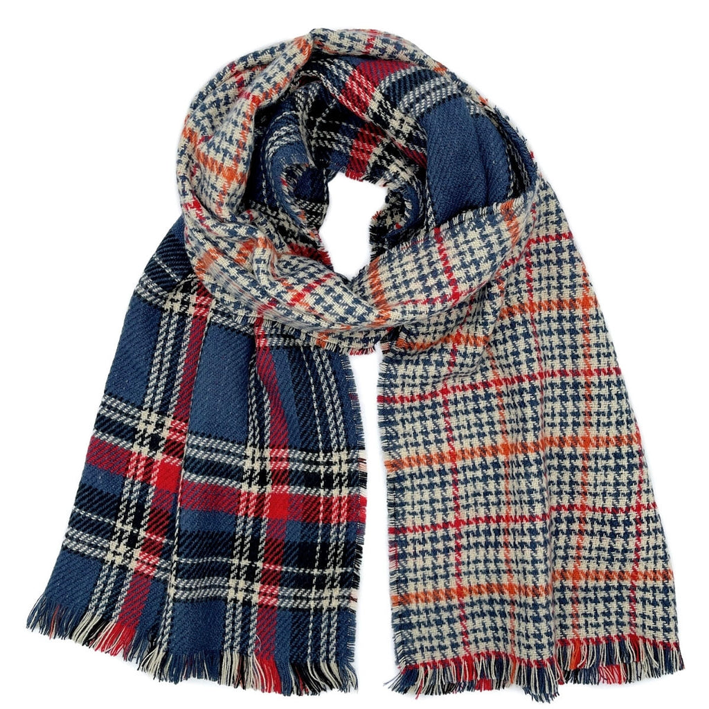 Reversible scarf loosely looped on a white background, displaying navy-and-red plaid beside cream-and-navy houndstooth with red and orange lines and multicolor fringe
