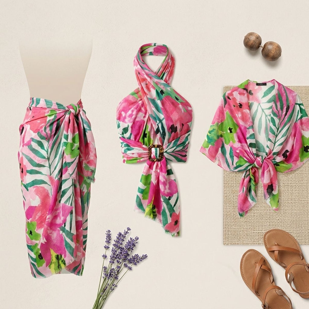 Styling display showing pink-and-green floral fabric as a waist wrap, a gathered halter-style arrangement with a buckle, and a tied-front garment beside sandals and dried stems