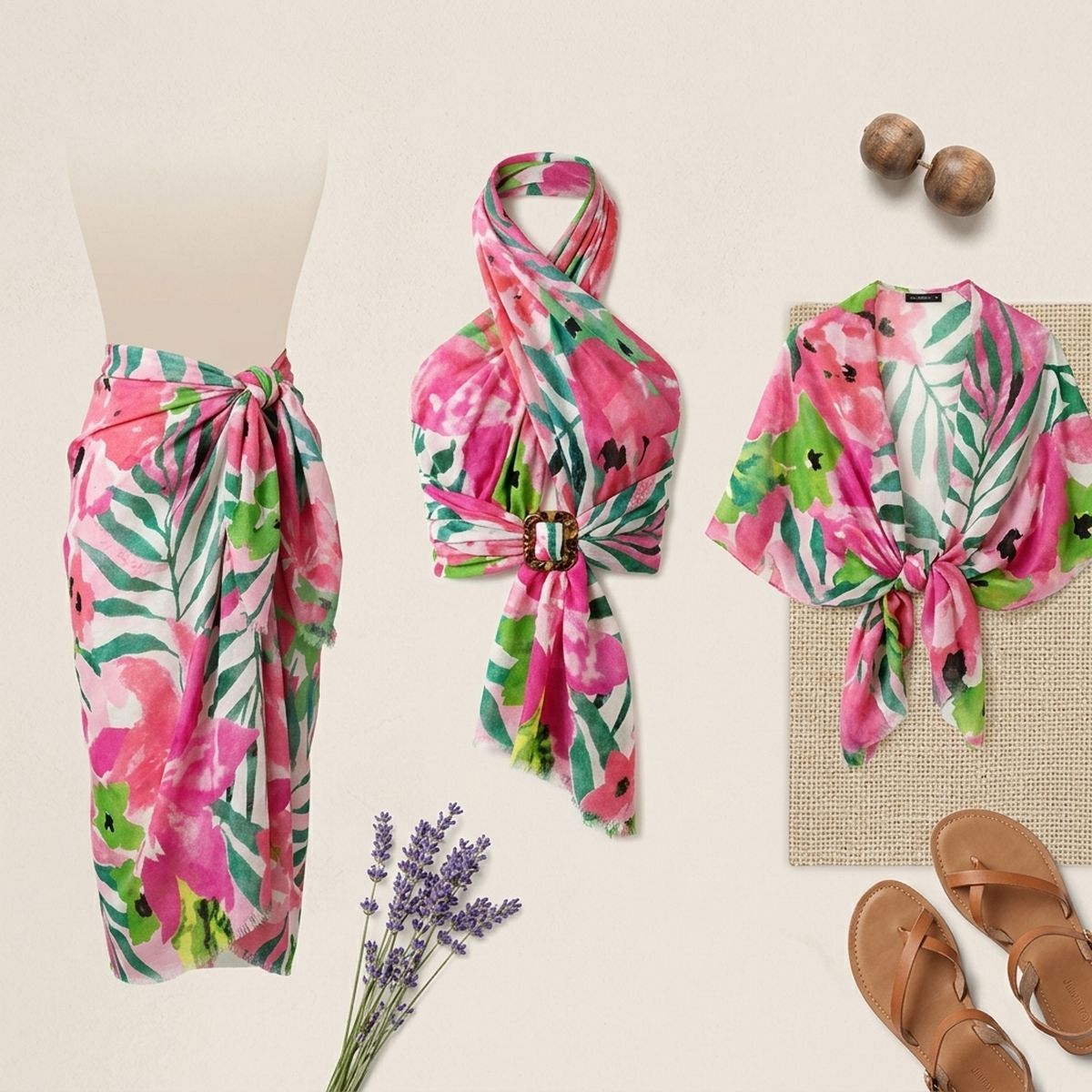 Styling display showing pink-and-green floral fabric as a waist wrap, a gathered halter-style arrangement with a buckle, and a tied-front garment beside sandals and dried stems