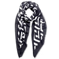 Black-and-white geometric print scarf loosely looped against a white background, showing its black border and fine frayed edges