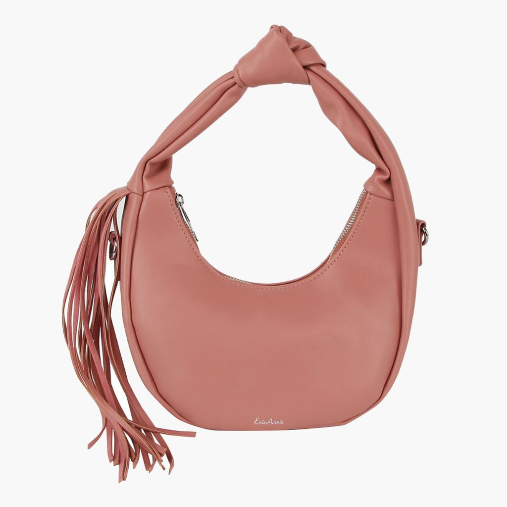 Blush pink crescent handbag with a knotted handle, long side tassel, and silver-tone zipper on a white background
