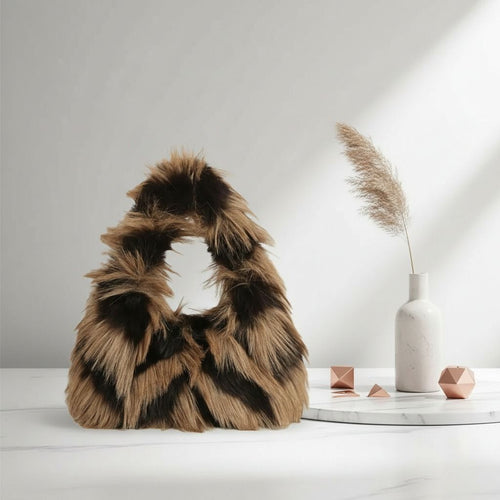 Brown-and-black striped faux-fur handbag displayed beside a white vase and decorative objects on a pale tabletop