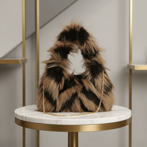 Brown-and-black shaggy faux-fur shoulder bag with a gold-tone chain displayed on a round white-and-gold table