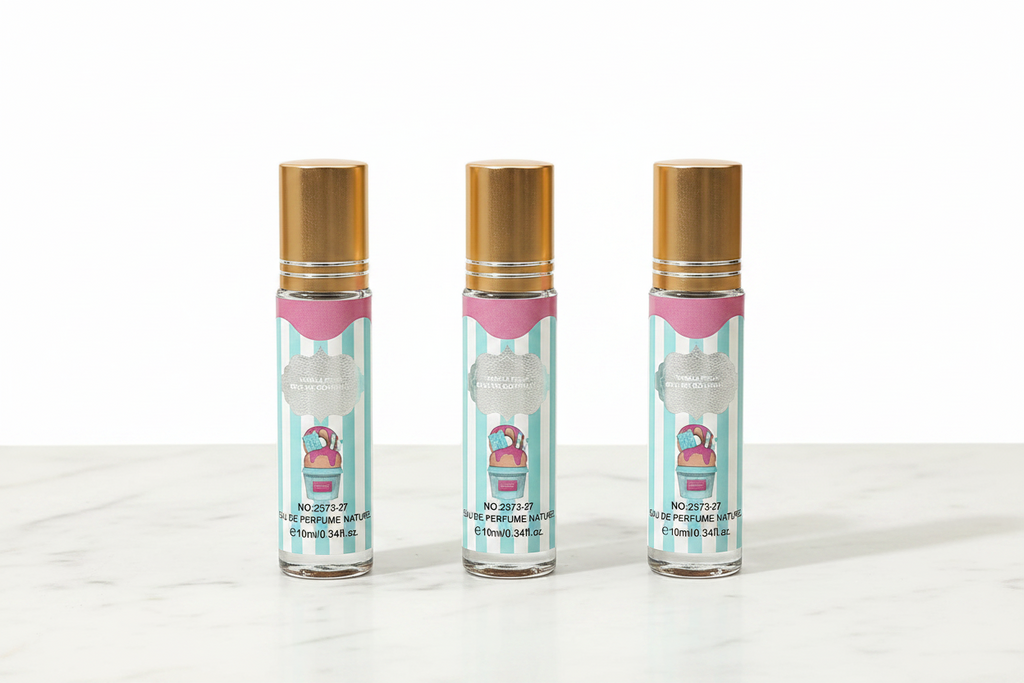Three 10ml mini eau de parfum roller bottles with gold caps, teal blue and white vertical stripe vanilla gourmand ice cream label, NO:2373-27, standing upright in a row on white marble surface, white background