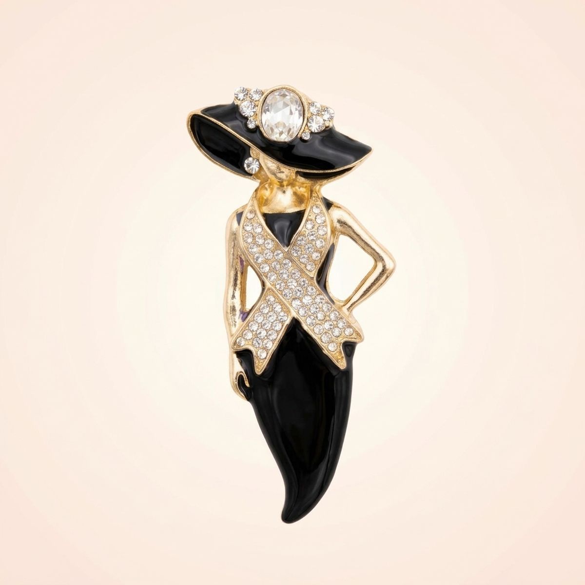 A fashion-themed brooch shaped like a woman in a black dress and hat with gold-tone outlines and clear rhinestones, set against a soft beige background.