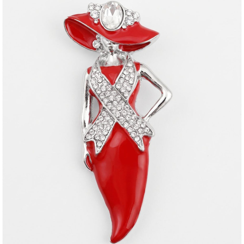 A fashion statement brooch shaped like a woman in a red dress and hat, embellished with silver-tone metal and clear rhinestones, set against a plain light gray background.