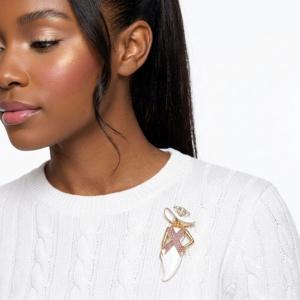 White hat lady pink ribbon brooch pinned on a woman's white cable-knit sweater near the collar