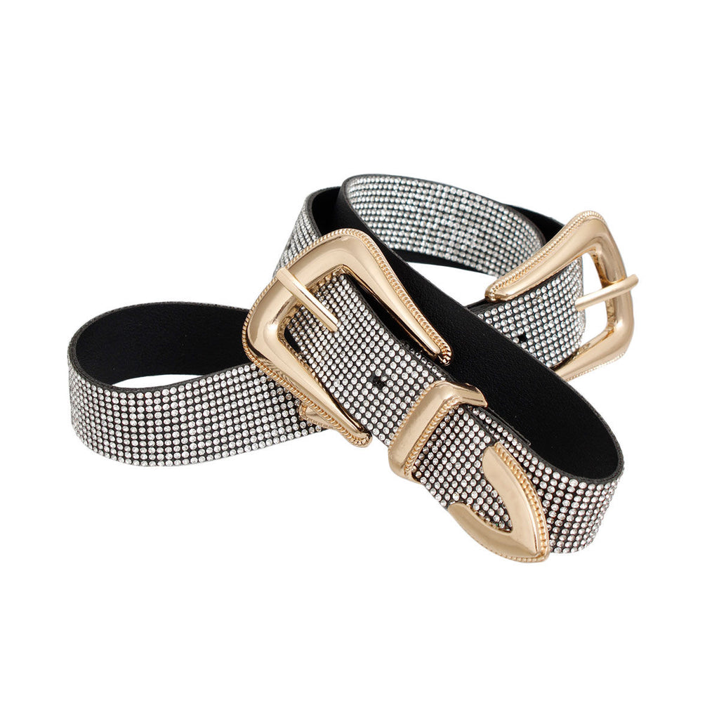 Full rhinestone clear crystal double buckle western belt coiled on white background showing both gold metal western buckles with pointed arrow tip hardware, micro clear crystal stone coverage across black vegan leather base, black suede-like underside visible