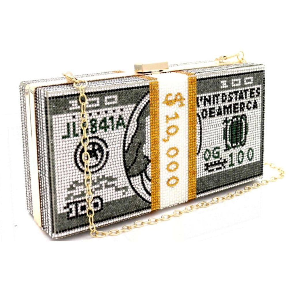 Angled view of a rectangular hardcase clutch fully covered in rhinestones, designed to look like a bound stack of $100 bills with a crystal "$10,000" currency strap, gold kiss-lock clasp, and gold chain strap draped across the front