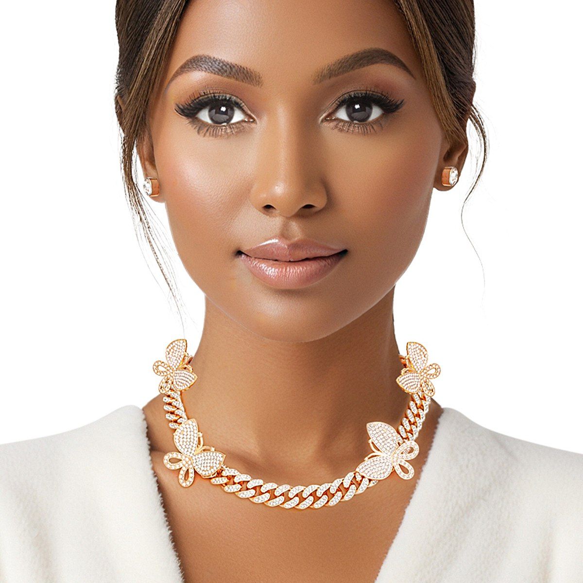 Woman wearing gold rhinestone-iced butterfly Cuban chain necklace with pave butterfly stations and small square stud earrings, white blazer, white background