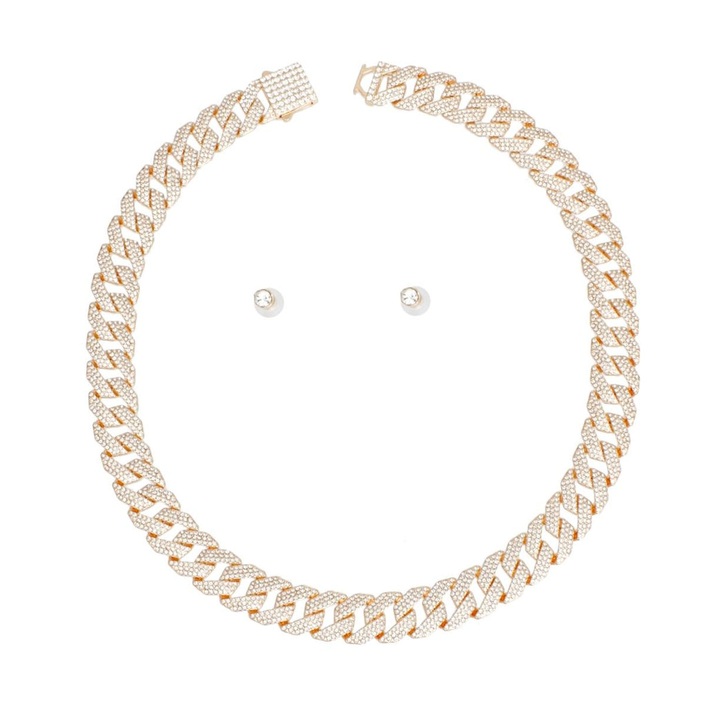 Overhead flat lay of a wide 14mm fully pave clear rhinestone Miami Cuban chain link necklace in gold tone arranged in a circle on a white background. A square push-lock box clasp covered in clear rhinestones is visible at the top with a safety latch. Two small round clear rhinestone stud earrings with butterfly post backings are displayed inside the necklace loop.