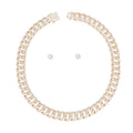 Overhead flat lay of a wide 14mm fully pave clear rhinestone Miami Cuban chain link necklace in gold tone arranged in a circle on a white background. A square push-lock box clasp covered in clear rhinestones is visible at the top with a safety latch. Two small round clear rhinestone stud earrings with butterfly post backings are displayed inside the necklace loop.
