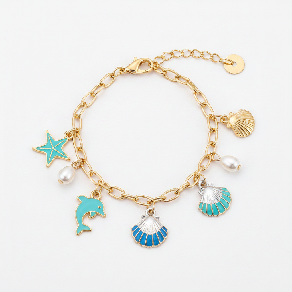Ocean seashell charm station bracelet in gold-tone, Starfish & Dolphin style — gold paperclip link chain with lobster claw clasp and gold disc extender, 5 dangling charms: teal enamel starfish, white pearl bead, teal enamel dolphin, blue and white striped scallop shell, and teal and white ribbed scallop shell, white background
