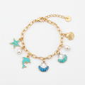 Ocean seashell charm station bracelet in gold-tone, Starfish & Dolphin style — gold paperclip link chain with lobster claw clasp and gold disc extender, 5 dangling charms: teal enamel starfish, white pearl bead, teal enamel dolphin, blue and white striped scallop shell, and teal and white ribbed scallop shell, white background