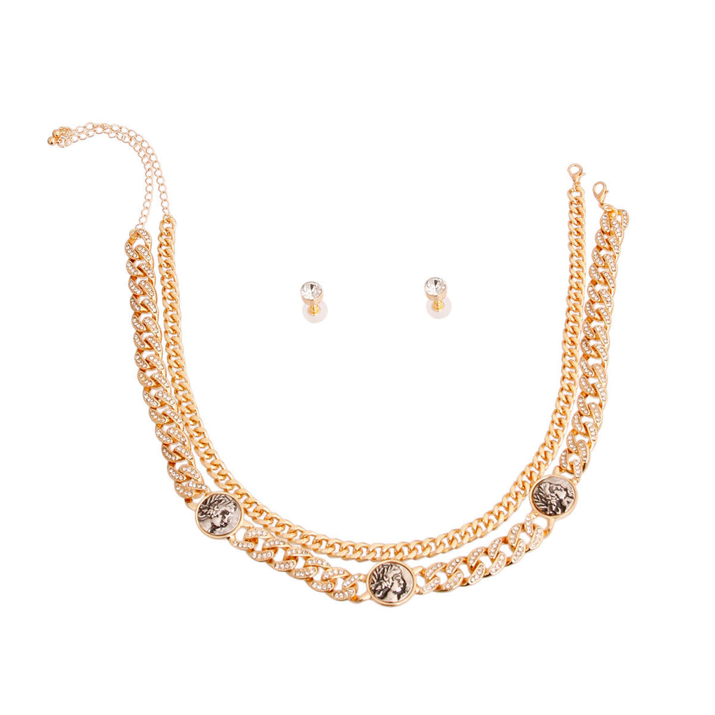 Overhead flat lay of a 2-layer rhinestone pave Cuban chain necklace in gold tone arranged in a U-shape on a white background. Three burnished antique gold coin medallions with a Roman profile face detail measuring 0.75 inches are spaced along the lower chain. A lobster clasp and extender chain are visible at the top right. Two small clear crystal round stud earrings with gold tone post backings are displayed in the center.